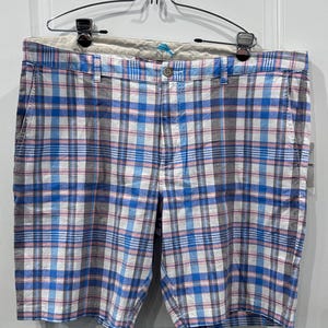 Peut inclure: Short short en tissu &agrave; carreaux bleus, blancs et roses, suspendu &agrave; un cintre en m&eacute;tal. Le short est dot&eacute; d'une fermeture boutonn&eacute;e et de poches. Le motif &agrave; carreaux est un design classique, adapt&eacute; au quotidien.