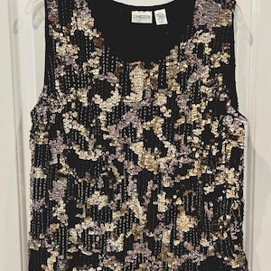 May include: Black sleeveless top with a scoop neckline, covered in gold and silver sequins. The top is from the brand Chico's. The sequins create a textured, shimmering effect, perfect for evening wear or special occasions.