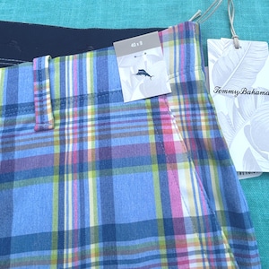 K&ouml;nnte beinhalten: Nahaufnahme von karierten Shorts in Blau, Rosa, Gelb und Wei&szlig;. Die Shorts haben ein Etikett mit der Aufschrift "Tommy Bahama" und ein weiteres Etikett mit den Ma&szlig;en "40 x 9" und einem Logo. Die Shorts sind aus leichtem Stoff.