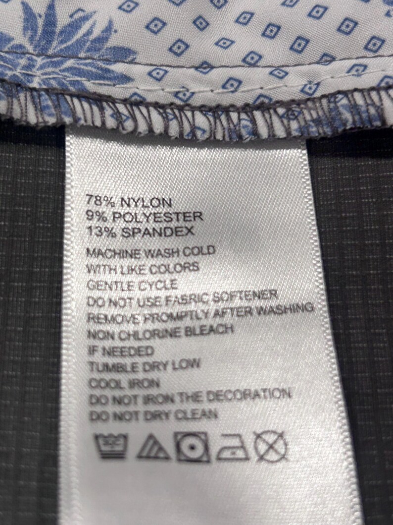May include: Close-up of a clothing label with care instructions. The label lists the fabric composition as 78% nylon, 9% polyester, and 13% spandex. Washing instructions include machine wash cold, gentle cycle, and tumble dry low.