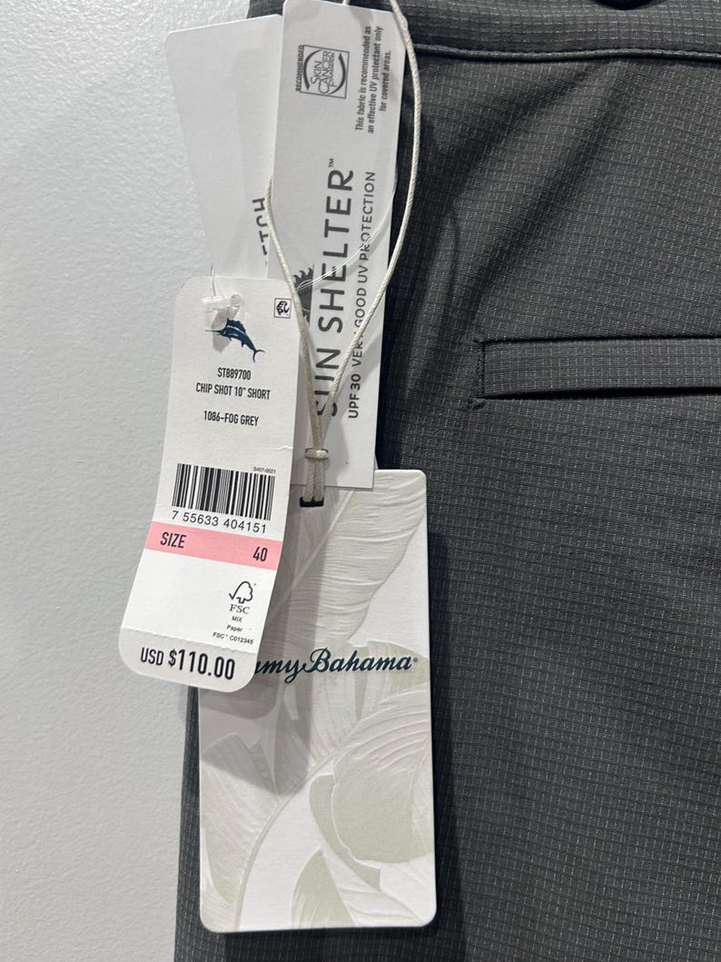 May include: Close-up of gray shorts with a tag. The tag reads "CHIP SHOT 10" SHORT" and "1086-FOG GREY". The tag also indicates "SUN SHELTER" with UPF 30 UV protection. The size is 40.