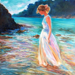 May include: An oil painting depicts a person in a white dress standing in shallow water at the edge of a beach. The artwork features a serene coastal scene with blue and turquoise water, rocky shores, and a bright sky.