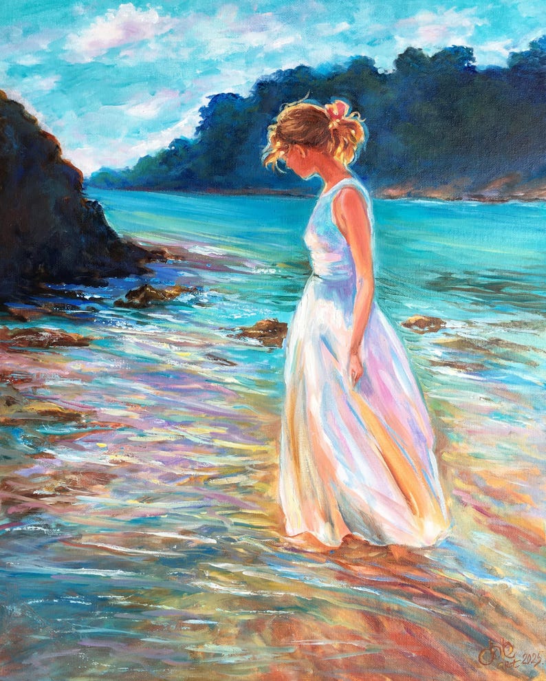 May include: An oil painting depicts a person in a white dress standing in shallow water at the edge of a beach. The artwork features a serene coastal scene with blue and turquoise water, rocky shores, and a bright sky.