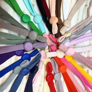 May include: A variety of colorful elastic mask extenders with different colored buttons. The extenders are made of a soft, stretchy material and are designed to make wearing a mask more comfortable.