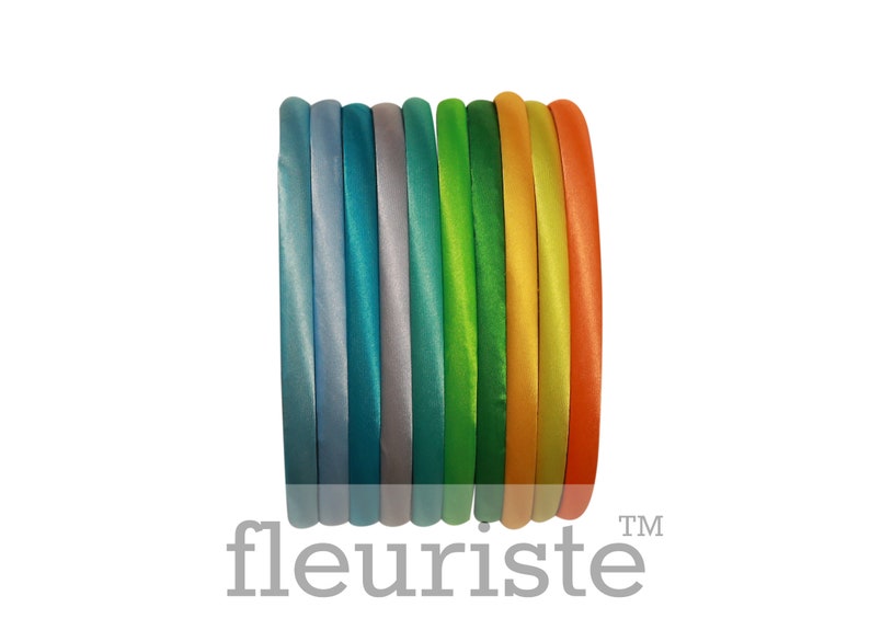 May include: A set of ten colorful satin headbands in shades of blue, green, yellow, and orange. The headbands are arranged in a stack, with the colors transitioning from light to dark.