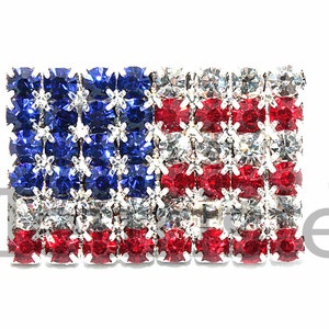 May include: A small American flag made of red, white, and blue rhinestones. The flag is about 1 inch wide and 2 inches long.