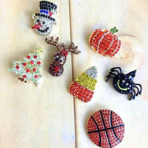 Può includere: Assortimento di sette spille natalizie con strass. Le spille raffigurano un pupazzo di neve, una renna, un albero di Natale, una zucca, mais dolce, una palla da basket e un ragno.