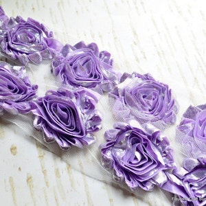 May include: Purple and silver flower trim with a mesh backing. The trim features multiple layers of fabric to create a 3D flower effect.