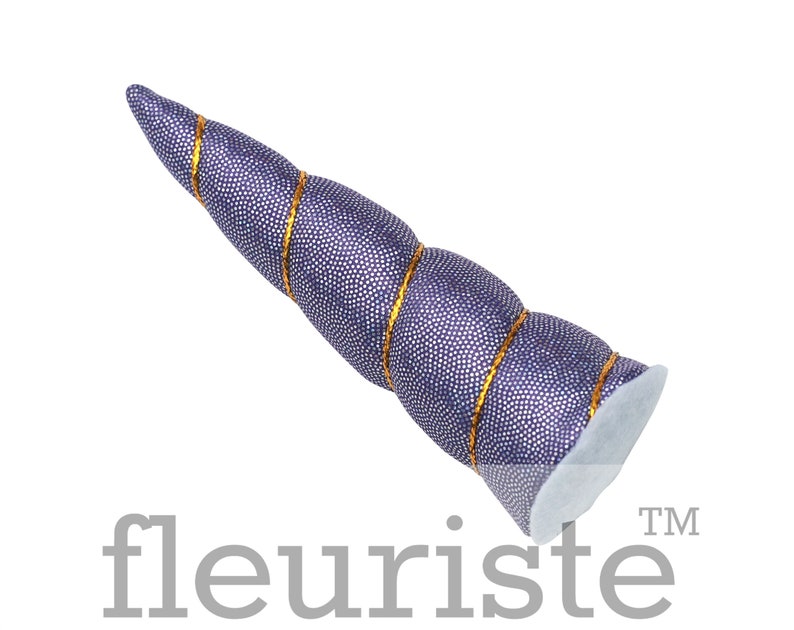 May include: Purple unicorn horn headband with gold glitter trim. The horn is made of fabric and is shaped like a spiral.