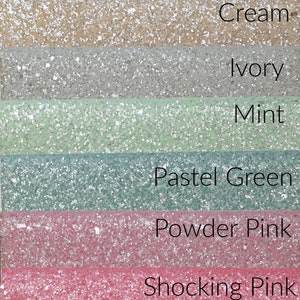May include: Seven swatches of glitter fabric in various pastel colors, including snow pink, cream, ivory, mint, pastel green, powder pink, and shocking pink. The fabric is labeled "fleurist&eacute;&trade;".