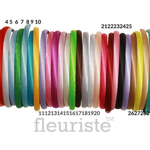May include: A set of 31 satin headbands in various colors, including purple, red, white, green, blue, yellow, pink, magenta, brown, gray, lavender, gold, and orange. The headbands are arranged in a row, with the numbers 1 through 31 printed below them. The text "fleuriste" is printed below the numbers.