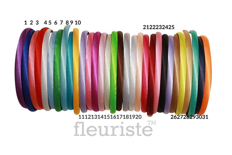 May include: A set of 31 satin headbands in various colors, including purple, red, white, green, blue, yellow, pink, magenta, brown, gray, lavender, gold, and orange. The headbands are arranged in a row, with the numbers 1 through 31 printed below them. The text "fleuriste" is printed below the numbers.