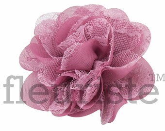 May include: A pink fabric flower with a delicate lace overlay. The flower is made of multiple layers of fabric and has a ruffled appearance.