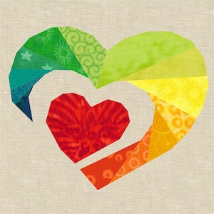 Könnte beinhalten: Ein farbenfrohes Patchwork-Herzdesign mit einem kleineren roten Herzen in der Mitte. Das Herz besteht aus Stoffresten in den Farben Grün, Gelb, Orange und Rot.