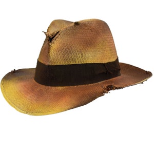 May include: A distressed fedora hat with a brown and yellow gradient. The hat features a dark brown band and shows signs of wear and tear, with frayed edges and holes. The hat is a classic accessory.