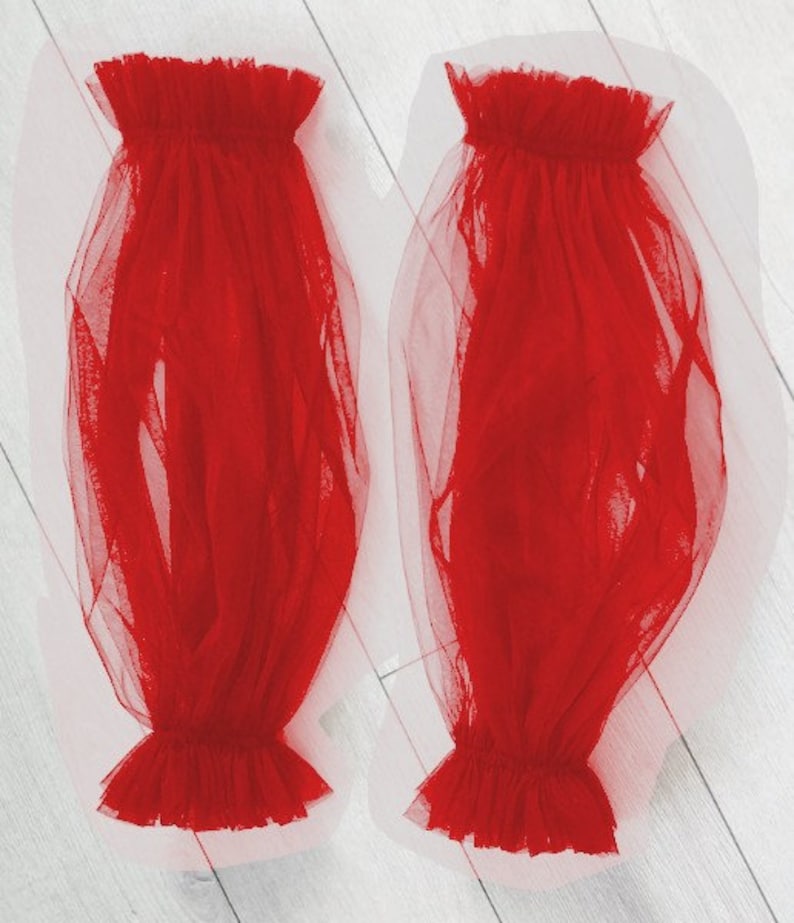 May include: A pair of red tulle sleeves with ruffled edges. The sleeves are sheer and flowy.