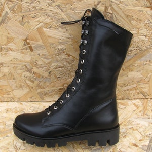 May include: Black leather lace-up boots with a chunky sole. The boots have a tall shaft and are made of a smooth leather.