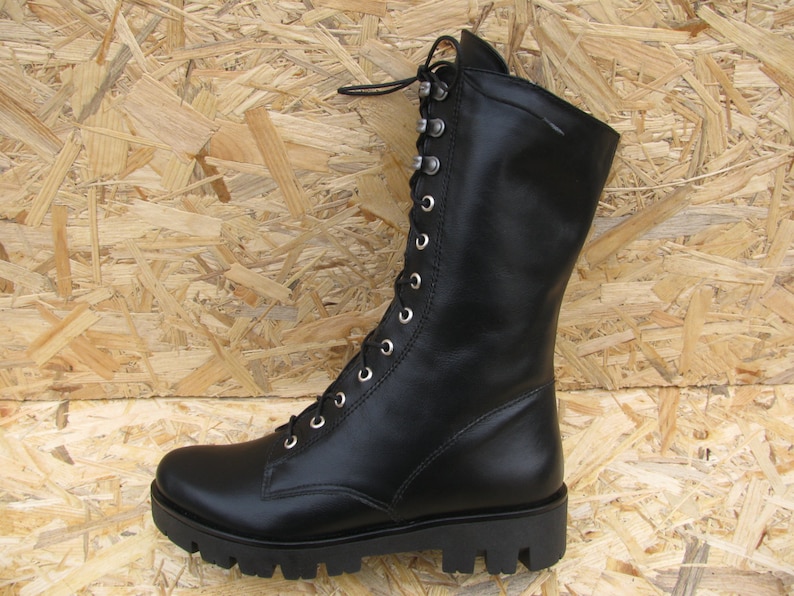 May include: Black leather lace-up boots with a chunky sole. The boots have a tall shaft and are made of a smooth leather.