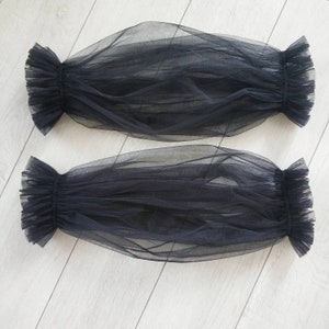 May include: Two black sheer tulle fabric arm warmers with ruffled edges.