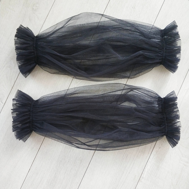 May include: Two black sheer tulle fabric arm warmers with ruffled edges.