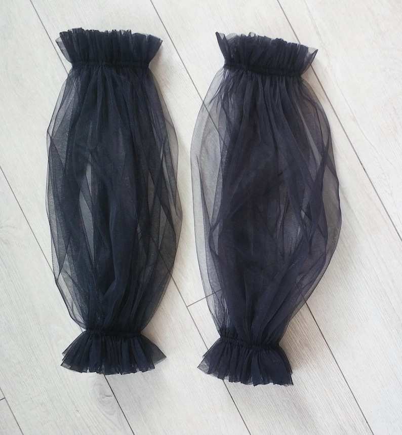 May include: A pair of black sheer mesh sleeves with ruffled edges.