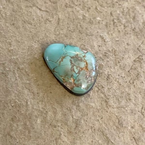 May include: A turquoise cabochon with a light blue and brown marbled pattern. The stone is cut in a heart shape.