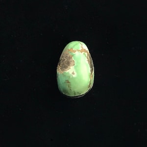 May include: A green and black oval cabochon gemstone with a marbled pattern.