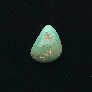 May include: A smooth, light green turquoise cabochon with brown and gold matrix. The stone is irregularly shaped and has a slightly pointed end.