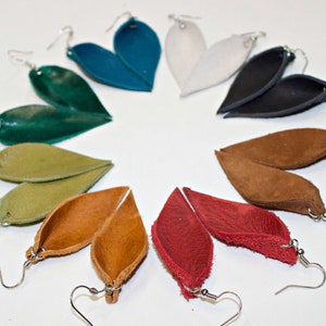 May include: Assortment of 10 pairs of leather earrings in various colors, including teal, green, white, black, brown, and red. The earrings are shaped like leaves and have silver hooks.