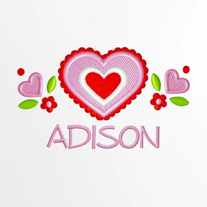 以下が含まれることがあります： ピンクと赤の刺繍されたハートの中に、さらに小さな赤いハートが刺繍されています。緑の葉と赤い花で囲まれ、その下に「ADISON」という名前が刺繍されています。