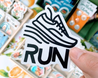 Könnte beinhalten: Ein weißer Aufkleber mit einer schwarzen Umrandung eines Laufschuhs und dem Wort "RUN" in schwarzen Buchstaben.