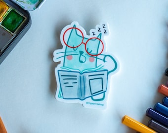 May include: A blue cat wearing red glasses and holding a book is sleeping. The cat is drawn in a cartoon style. The text "zzz" is above the cat's head. The text "@mgsprintshop" is below the cat.