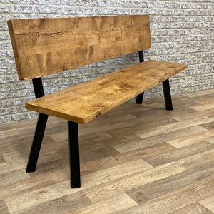 May include: A wooden bench with a backrest and black metal legs. The bench is made of reclaimed wood and has a natural finish.