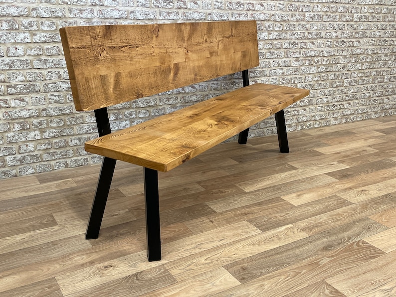 May include: A wooden bench with a backrest and black metal legs. The bench is made of reclaimed wood and has a natural finish.