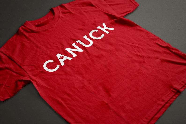 May include: Red t-shirt with the word "CANUCK" printed in white with a Canadian maple leaf in the "C".