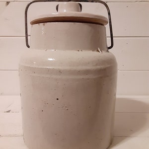 Puede incluir: Crock de cer&aacute;mica blanca con asa de alambre met&aacute;lico y tapa. El crock tiene un acabado esmaltado y est&aacute; ligeramente desgastado.