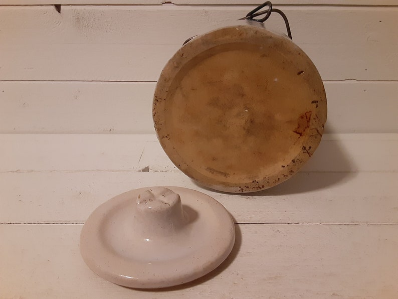 Puede incluir: Un tarro de cer&aacute;mica blanco con tapa. El tarro tiene un esmalte marr&oacute;n y un interior blanco. La tapa tiene un peque&ntilde;o pomo en la parte superior.