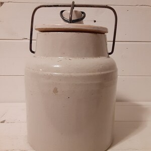 Puede incluir: Un tarro de cer&aacute;mica blanco con un asa de alambre met&aacute;lico y tapa. El tarro tiene un dise&ntilde;o sencillo y es perfecto para almacenar alimentos.