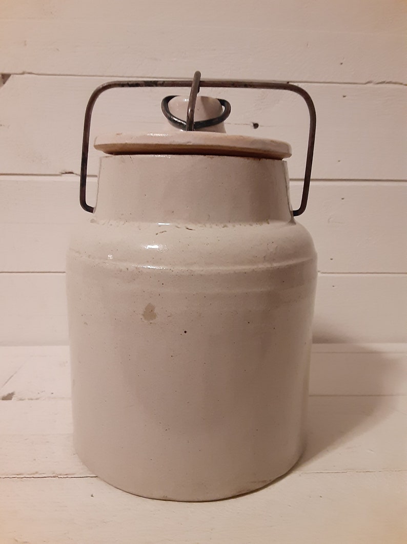Puede incluir: Un tarro de cer&aacute;mica blanco con un asa de alambre met&aacute;lico y tapa. El tarro tiene un dise&ntilde;o sencillo y es perfecto para almacenar alimentos.