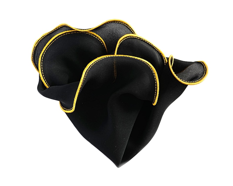 May include: A black pocket square with a yellow stitched border. The pocket square is folded and has a ruffled edge.