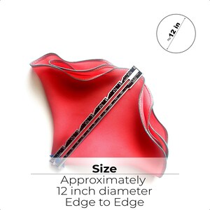 May include: A bright pink fabric circle with a ruffled edge, measuring approximately 12 inches in diameter. The fabric is folded in half and a ruler is placed on top of it.