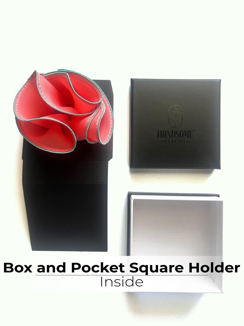 May include: A black box with the text "HANDSOME" on the lid. Inside the box is a white box with a pink pocket square folded inside. The pocket square has a teal trim.