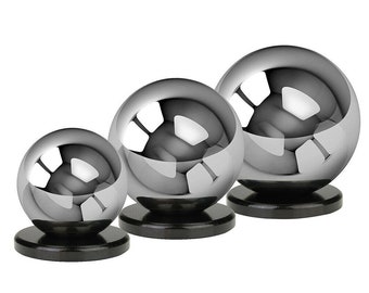 May include: Three silver spheres of different sizes on black bases. The spheres are highly reflective and appear to be made of metal.