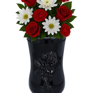 May include: A black urn with a floral arrangement of red roses, white daisies, and red carnations. The urn features a rose design and the text "REMEMBER FOREVER UNIQUE URNS FOR ASHES".
