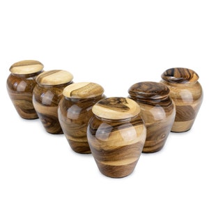 May include: Six wooden urns in a row, each with a unique wood grain pattern. The urns are brown and have a glossy finish.