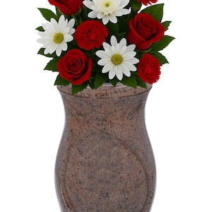 Könnte beinhalten: Eine braune Urne mit einem Blumenarrangement aus roten Rosen, Nelken und weißen Gänseblümchen. Die Urne hat ein gesprenkeltes Muster und eine geschwungene Form. Ein Schild über den Blumen lautet "REMEMBER FOREVER UNIQUE URNS FOR ASHES."