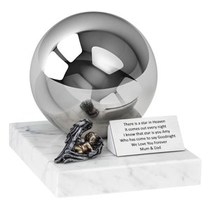 Può includere: Una sfera commemorativa argentata con una piccola statuina di angelo su una base di marmo bianco. La base ha una targa con l'iscrizione "There is a star in Heaven It comes out every night I know that star is you Amy Who has come to say Goodnight We Love You Forever Mum & Dad".