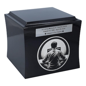 May include: Black wooden cremation urn with a silver plaque that reads "In Loving Memory of Timothy Smith August 12, 1982 - April 26, 2024 Always in Our Hearts ❤". The urn features a silver design of a person sitting at a computer.