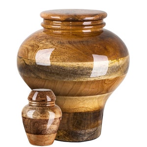 Op de afbeelding: Twee houten urnen, een grote en een kleine, met een natuurlijk houtnerfpatroon en een glanzende afwerking. De urnen zijn gemaakt van verschillende houtsoorten, wat een uniek en prachtig ontwerp creëert.