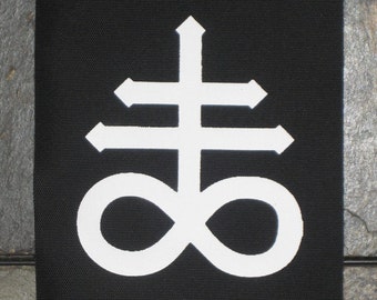 Könnte beinhalten: Schwarzer Patch mit einem weißen Symbol. Das Symbol ist ein Kreuz mit einem Unendlichkeitszeichen am unteren Ende.